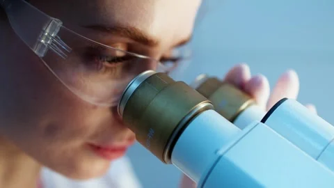 Scientist examining samples through a microscope, focusing on the eyepiece while Stock Footage 334884531