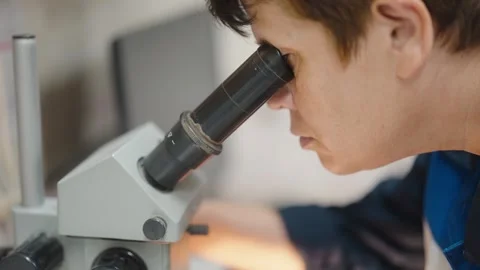 Scientist examining samples under a microscope in a laboratory setting Video stock 275583653