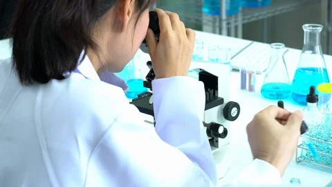Scientist female is looking through microscope with colleagues working in lab. Video stock 108777026