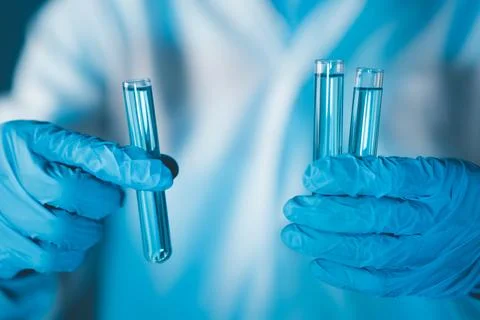 Scientist hand hold test tubes filled with blue sample chemicals in chemist.. Stock Photos
