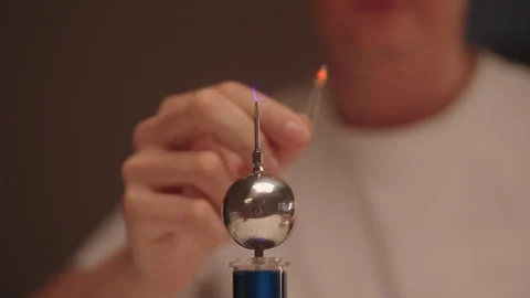 Scientist hands holding two leds near mini tesla coil, observing electrostatic Stock Footage 326469115