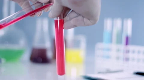 Scientist hands mixing red and yellow chemicals in test tube HD Stock Footage