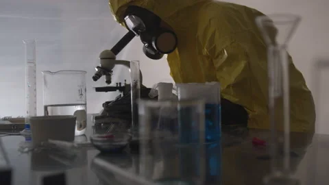 Scientist in Hazmat Suit Observing Elements Through a Microscope Video stock 208753598