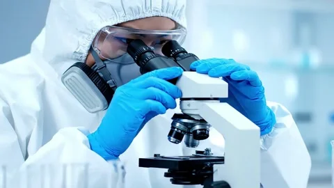 Scientist in Hazmat Suit Using a Microscope in a Lab. Stock Footage 316886113