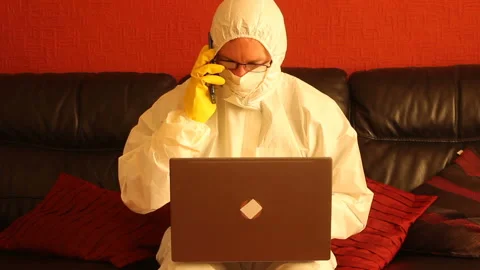 Scientist in hazmat suit working on a computer receiving a phone call - zoom in Stock Footage 135722408