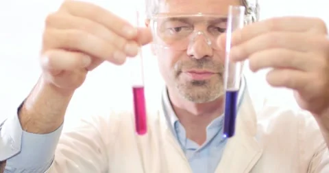 A scientist holding and looking at two test tubes with some chemicals in it Stock Footage 48976649