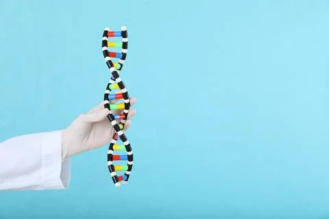 Scientist holding DNA structure model on light blue background, closeup. Sp.. 写真素材