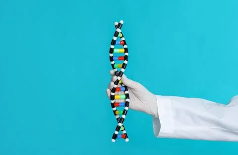 Scientist holding DNA structure model on light blue background, closeup Foto stock