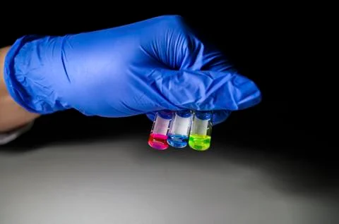 Scientist holding three colourful solution in different LCMS glass vial on a  Stock Photos