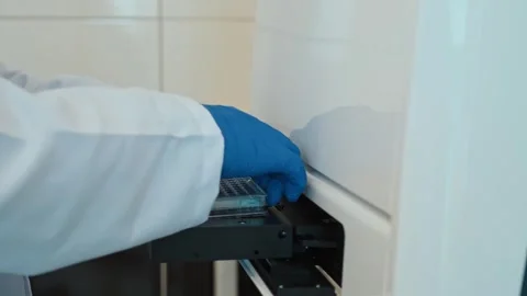 Scientist Inserting Microplate into Laboratory Analyzer for Sample Testing Video stock 308044069