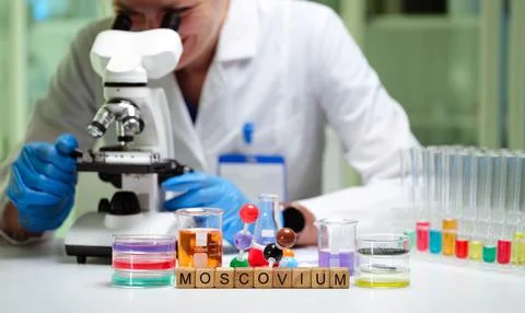 A scientist is investigating elements with a microscope and chemical samples to Foto stock