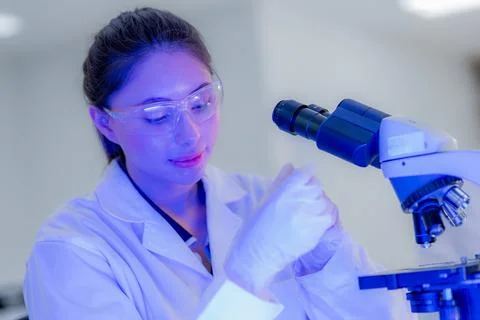 Scientist in lab coat using microscope to examine samples in laboratory env.. Stock Photos