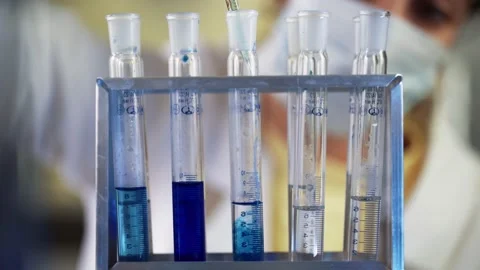 Scientist in laboratory doing chemical experiment with blue liquid in test tubes Stock Footage 145427539