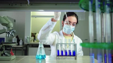 Scientist in laboratory doing chemical experiment with blue liquid in test tubes Stock Footage 145519272