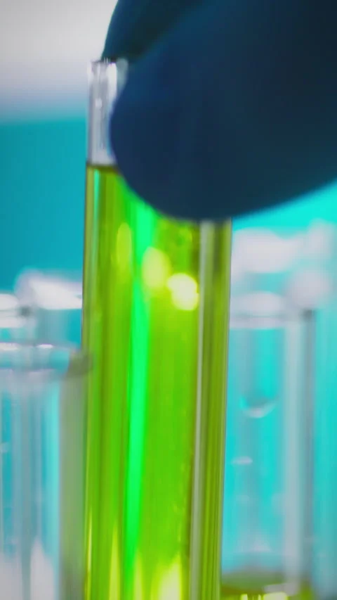 Scientist in laboratory handling test tubes with green liquid during researc Stock Footage 331725700
