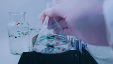 Scientist in a laboratory removing a beaker with microplastic polluted water fro Vídeos de archivo 331322346