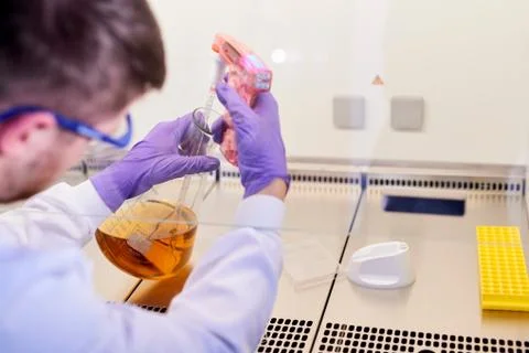 Scientist in laboratory using electronic pipette in conical flask Foto stock
