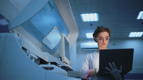 Scientist in laboratory wearing gloves analyzes data on laptop while interacting Stock Footage 334884683