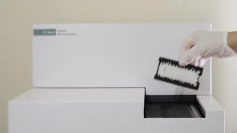 A scientist loads samples into a scanner for microarray analysis. Stock Footage 294563786