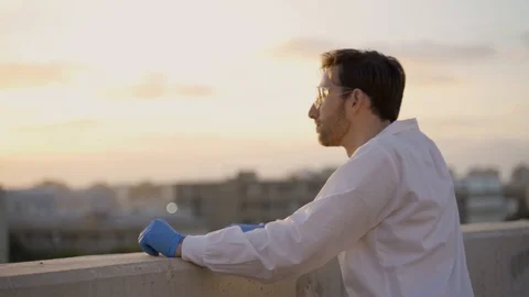 Scientist looking at the horizon over a lab building during sunset or sunrise Stock Footage 112620131