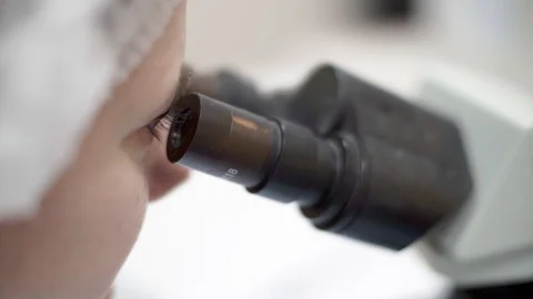 Scientist looking into microscope. Close up shot in lab. 動画素材 110810740