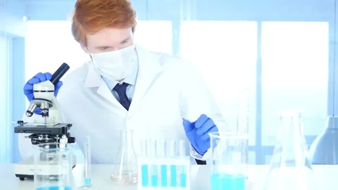 Scientist Looking at Test Tube blue Solution and using Microscope in Laborato Stock Footage 80944721