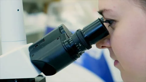 Scientist looking through a microscope and examining a new dangerous virus Stock Footage 103715612