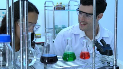 Scientist is looking through microscope with colleagues working in modern lab. Stock Footage 106867614
