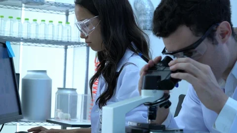 Scientist is looking through microscope with colleagues working in modern lab. Stock Footage 106867867