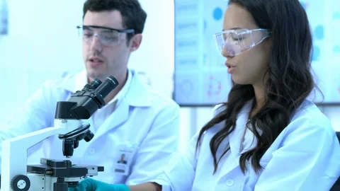Scientist is looking through microscope with colleagues working in modern lab. Stock Footage 109128156