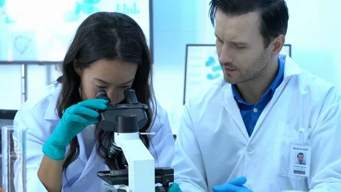 Scientist is looking through microscope with colleagues working in modern lab. Stock Footage 109134803