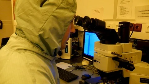 A scientist looking through a microscope, in a a futuristic looking Vidéo 94569988