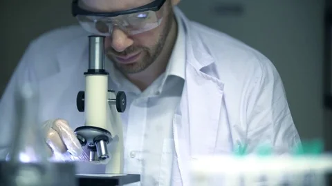 Scientist Looking Through a Microscope in a Laboratory, Young Male in 4K Stock Footage 77960278