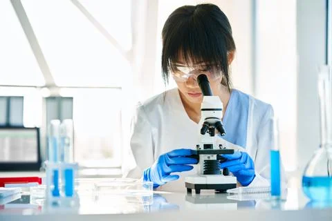 Scientist looking through a microscope working in science laboratory Stock-Fotos