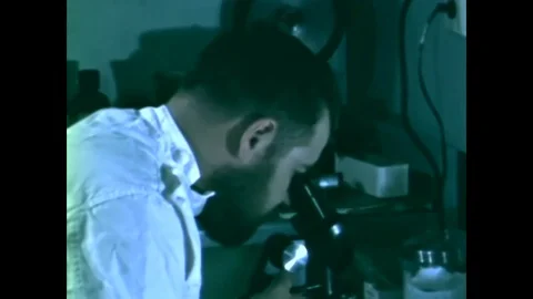 A scientist looks into a microscope, maps are viewed and radio communication is Stock Footage 79419578