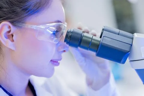 Scientist looks through a microscope in a laboratory during a research sess.. Stockfoto's