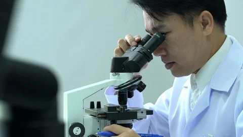 Scientist male is looking through microscope working in modern laboratory Stock Footage 108713301