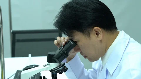 Scientist male is looking through microscope working in modern laboratory Video stock 108714758