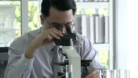 Scientist man is looking through microscope Stock Footage 177944045