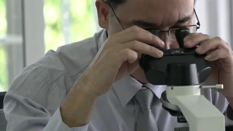 Scientist man is looking through microscope Stock Footage 177947313
