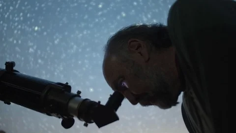 Scientist man looking through telescope with stars swirling effect in backgro Stock Footage