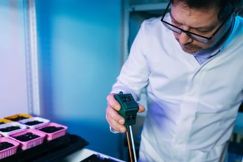 Scientist measuring acidity and pH of soil at table, closeup. Laboratory Stock Photos