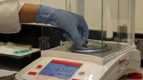 Scientist measuring the weight of a syringe on a digital weight scale Stock Footage 155118253