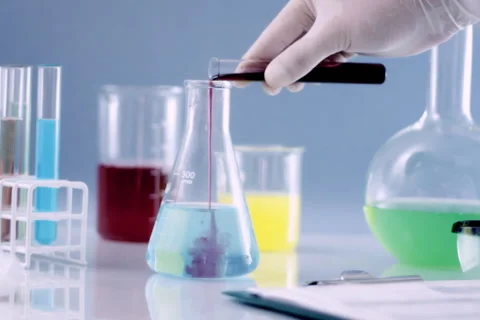 Scientist mixing chemicals in Erlenmeyer flask, and writing results in clip NTSC Stock Footage