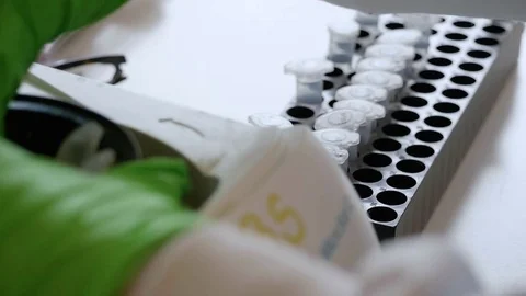 Scientist moving vile's in a laboratory from a machine to a tray 库存影片 73484208