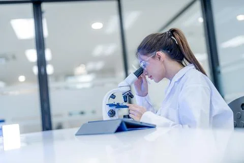 Scientist observes sample through microscope in laboratory setting during d.. Stock Photos