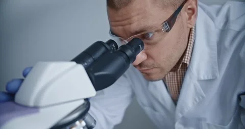 Scientist observes samples through microscope to draw conclusions Vídeo Stock 299903224