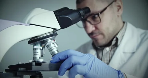 Scientist observes samples through microscope to draw conclusions 動画素材 299903298