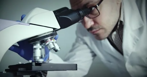Scientist observes samples through microscope to draw conclusions 스톡 동영상 299903456