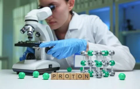 A scientist observing protons through a microscope in a lab for research and Foto stock